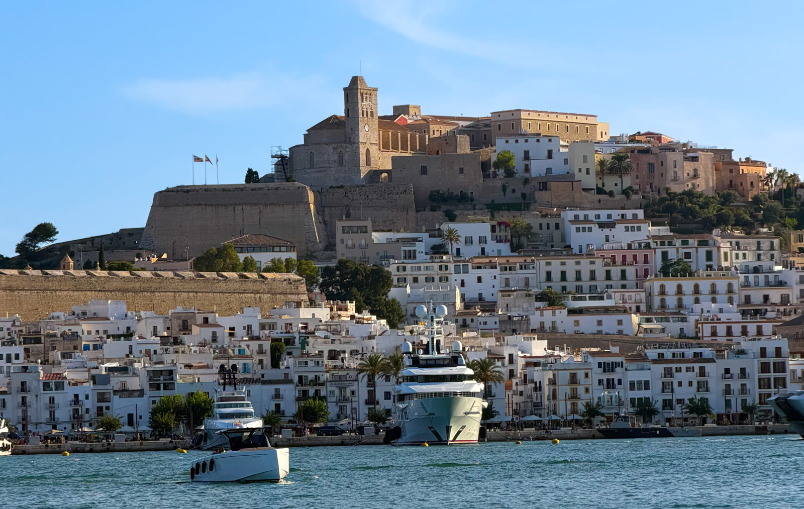 Dalt Vila's fortified old town and Ibiza Cathedral seen from the harbour, with a boat crossing the bay